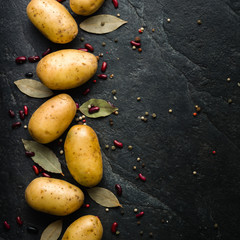 A pile of raw potatoes on a dark stone background. Preparation of soup or potato dishes.