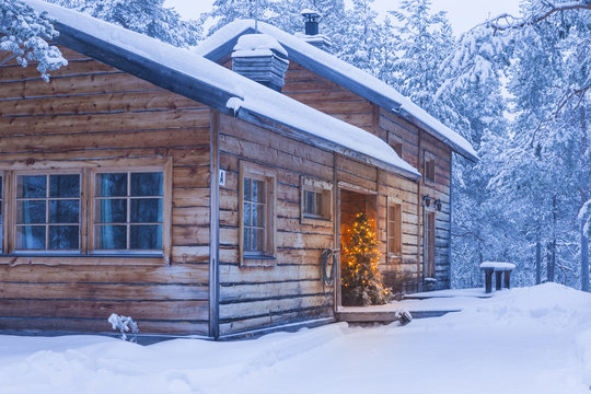 Travel Destinations Concepts. Cosy Wooden House with Christmas Tree in Front Located in Tranquil Picturesque Nordic Forest in Scandinavia At Christmas Time