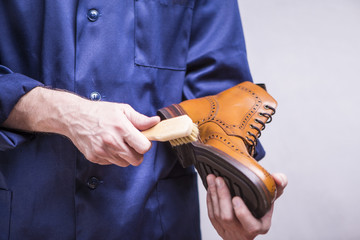 Footwear Concepts and Ideas. Man with Cleaning Brush For Premium Tan Derby Boots. Making Cleaning.