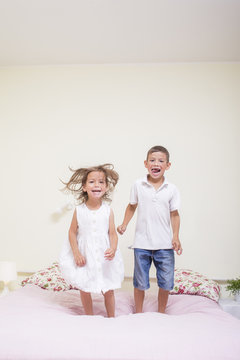 Family Values and Relationships. Happy Kids Playing Indoors. Jumping On The bed Together.Vertical Image Composition
