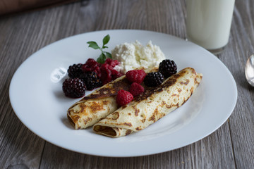Crepes stuffed with cheese and strawberry topping on a white plate