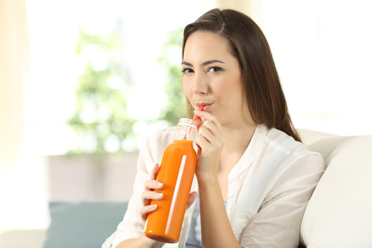 Girl drinking a carrot or orange juice from a bottle