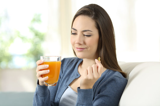 Woman holding an orange juice and vitamin pill