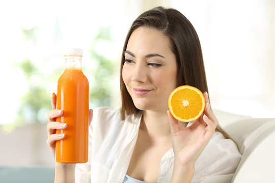 Woman showing an orange and a juice bottle