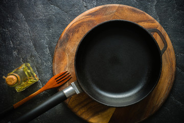 A black cast-iron frying pan for cooking food. Vegetable oil with spices.