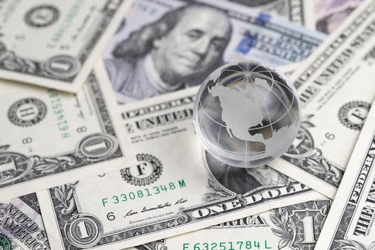 United States Financial Anti Globalization Or Center Of World Economic Concept, Shiny Decoration Glass Globe On Pile Of US Dollar Banknotes