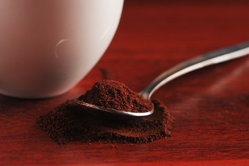 A spoonful of ground coffee lies on the table. Against the backdrop of a cup. Dark kitchen In a low...