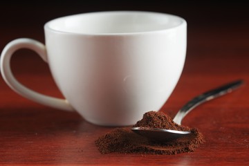 A spoonful of ground coffee lies on the table. Against the backdrop of a cup. Dark kitchen In a low...