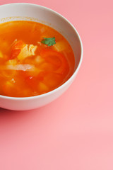 Hot vegetable soup with chicken meat in a bowl. a leaf of greenery. on a pink background. The concept of a healthy food and diet