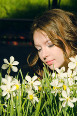 Naklejka premium woman in boho style dress sat down to relax near the flowerbed with daffodils in the Park