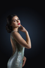 beauty fashion portrait of a beautiful model in an evening dress embroidered with stones. Girl on a black background. Shining stones and crystals.