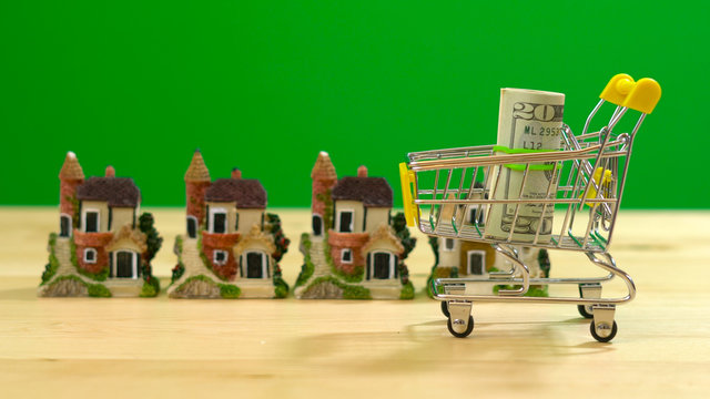 E-commerce retail estate shopping for houses concept with miniature shopping cart against chroma key background.