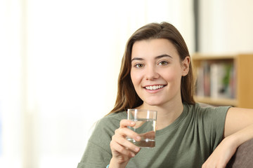 Happy teen holding a glass of water looking at you