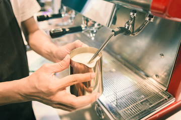 Barista made foam milk by coffee machine with vintage tone.
