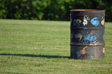 an artistic trashcan in the park with painted handprints