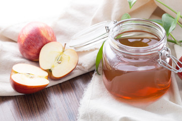 Closeup of glass jar apple juice with fresh apples on table