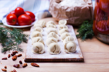 Obraz na płótnie Canvas dumplings with meat on a wooden stand - cooking, raw unpeeled dumplings, national Russian, Ukrainian cuisine