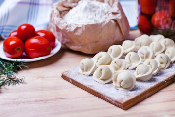 dumplings with meat on a wooden stand - cooking, raw unpeeled dumplings, national Russian, Ukrainian cuisine