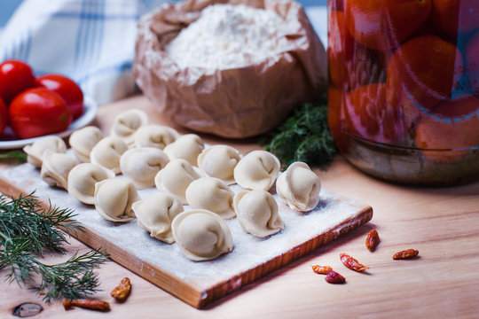 dumplings with meat on a wooden stand - cooking, raw unpeeled dumplings, national Russian, Ukrainian cuisine