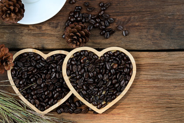 Roasted coffee beans in wooden heart tray, stacked 2 pieces on wooden floor. Coffee lovers concept