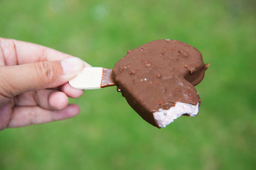 Ice cream chocolate heart in hand with blurry background