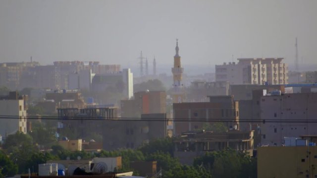 Zoomed-in view of Khartoum, Sudan showing houses, trees, a mosque minaret and industry towers in the background