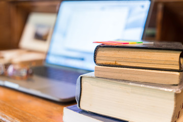 Working classic wooden desk  with books and soft background of laptop
