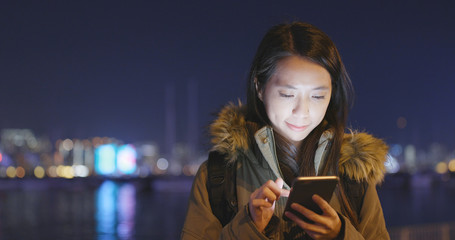 Obraz na płótnie Canvas Woman using cellphone in city at night
