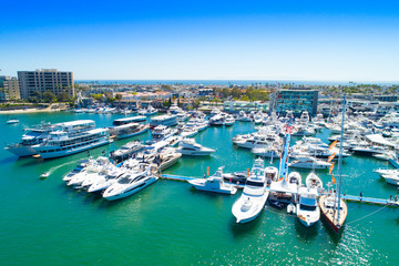 Cinematic aerial view over the Newport Beach harbor during the annual boat show with luxury yachts, boats and Duffy boats on a sunny blue sky day. - Powered by Adobe