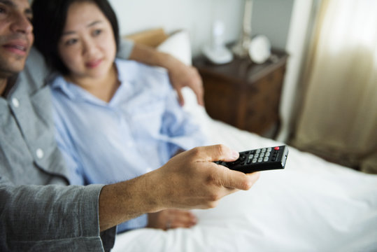 A Couple Watching Tv Together In Bed