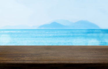Empty old dark wood table top with blur blue sky and sea bokeh background,Mock up template for display or montage of product or content use as banner in social media ads