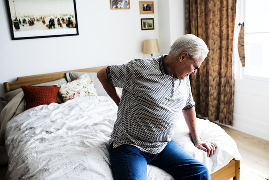 Senior man sitting on the bed in pain