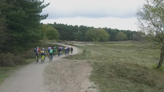 Drone follows a group of cyclocross cyclists as they enter the woods.