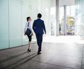 Asian business people discussing while walking - obrazy, fototapety, plakaty