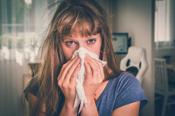 Sick woman with flu or cold sneezing into handkerchief - obrazy, fototapety, plakaty