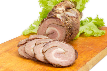Baked rolled up pork belly on a cutting board closeup