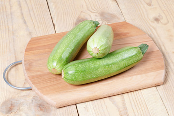 Courgettes zucchini on cutting Board on wooden table