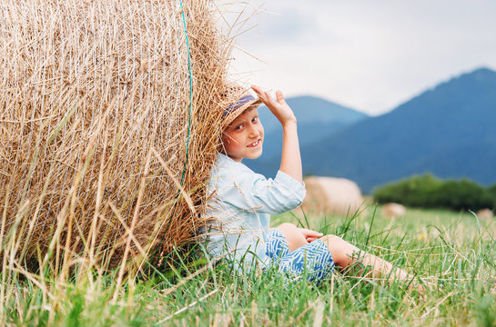 Boy sit on the fiild under the hay roll - careless summet in country side