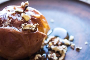 dessert with baked apple of honey and nuts on a clay plate