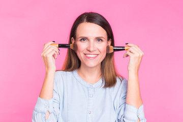 Professional makeup artist with brushes on pink background