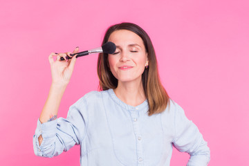 Professional makeup artist with brushes on pink background