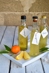 Three delicious yellow alcohol drinks in glass bottles and citrus fruit. Orange-flavored liqueur,...