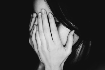 Obraz premium Crying young girl covers her face with hands black white