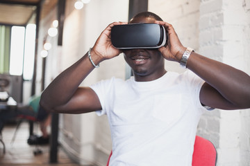 Young man wearing virtual reality glasses in modern interior design coworking studio. Smartphone using with VR goggles headset