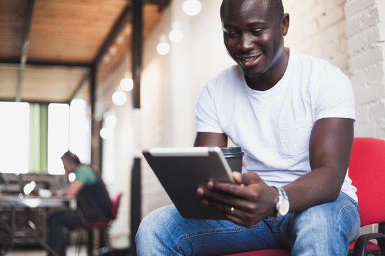Smiling African man using tablet for video conversation in modern office.