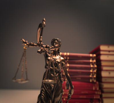 justice statue in front of a pile of law books
