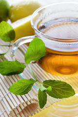 Tea in the glass cup with lemon and fresh mint leaves - herbal healing tea as homemade remedy