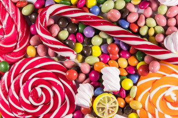 Fototapeta na wymiar Background of colorful chocolate candies, lollipops, candy cane and marshmallows