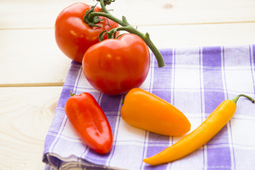 Cooking concept - red and yellow pappers and tomatos on wooden table. Set of healthy food products are sources of vitamins and minerals. Closeup