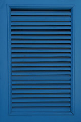 Large window closed by blue shutters. Vertical photo